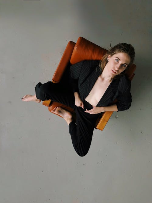 Woman in Black Blazer Sitting on Brown Leather Sofa