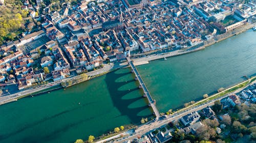 Drone view of coastal city located near calm river with bridge in daytime