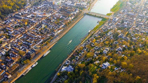 Drone view of long river with bridge flowing along town on bay in daytime