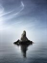 Distant stony steep cliff located in calm rippling water surface under clear sky
