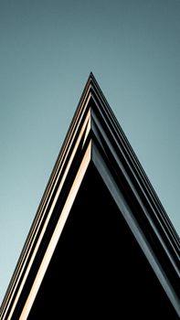 Modern building corner with sharp angles contrasting against a clear blue sky.