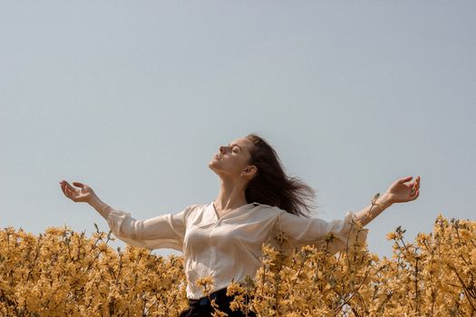 晴朗的天空下，一位女士张开双臂，享受宁静的户外生活