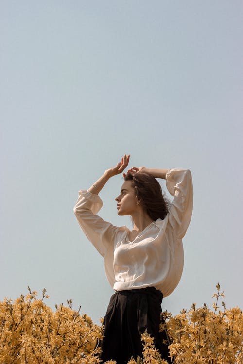 Woman in White Long Sleeve Shirt Standing on Flower Fields