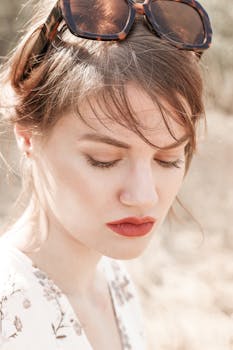 Stylish woman with sunglasses and floral dress, enjoying a sunny day outdoors. Fashionable and serene portrait.