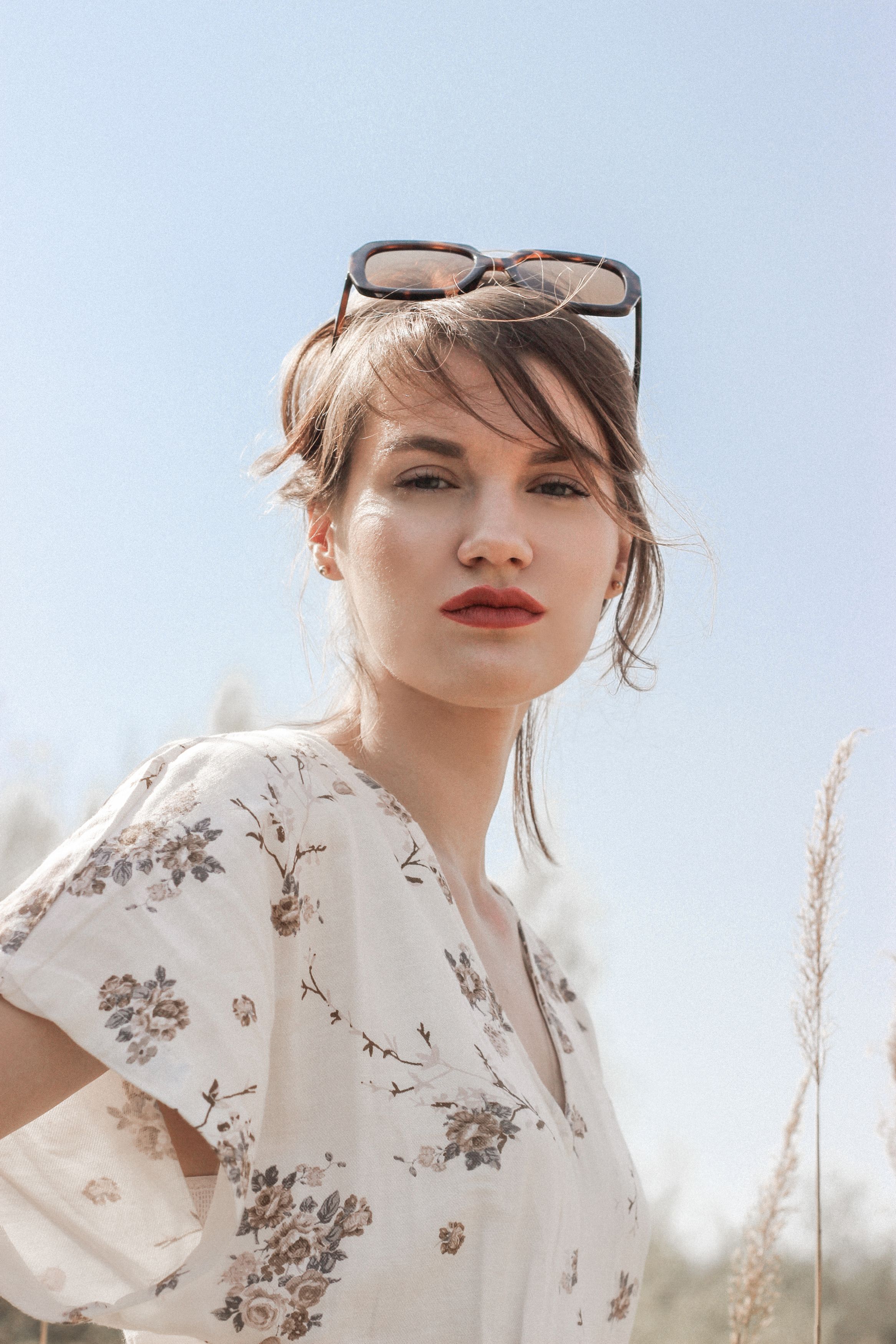 Woman in White Floral Dress Sitting on Brown Grass Field · Free Stock Photo