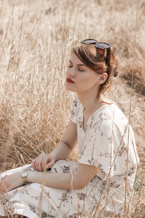Woman in White Floral Dress Sitting on Brown Grass Field · Free Stock Photo