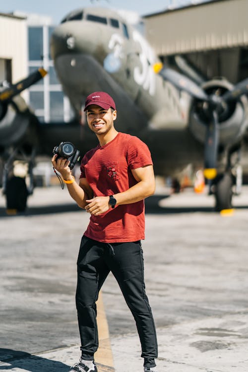 Happy young ethnic guy exploring vintage aircraft during trip