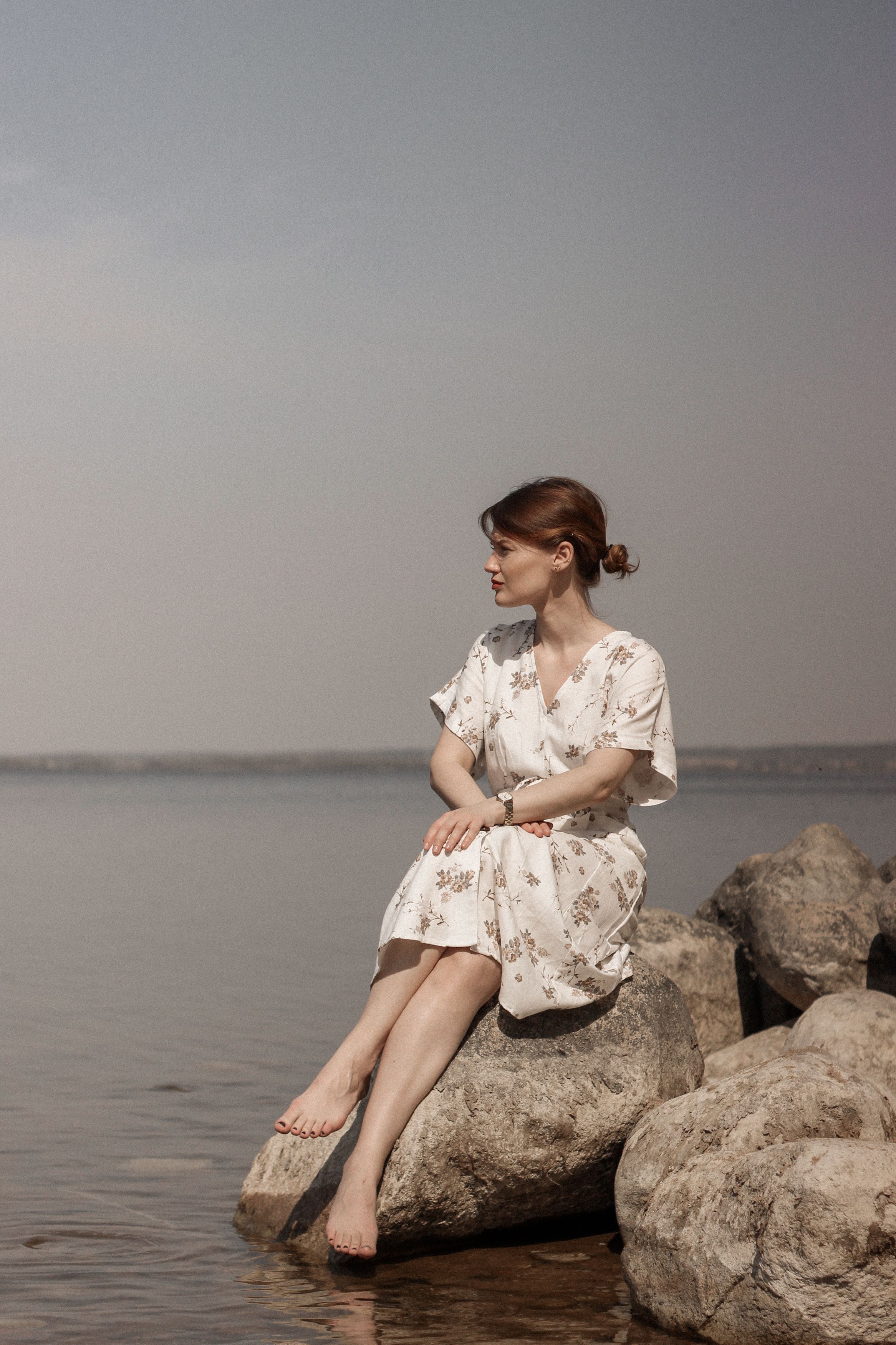 Woman in White Dress Sitting on Rock Near Body of Water · Free Stock Photo