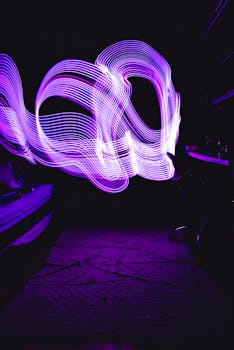 Dynamic purple light painting creating vivid waves on a dark backdrop, perfect for abstract designs.