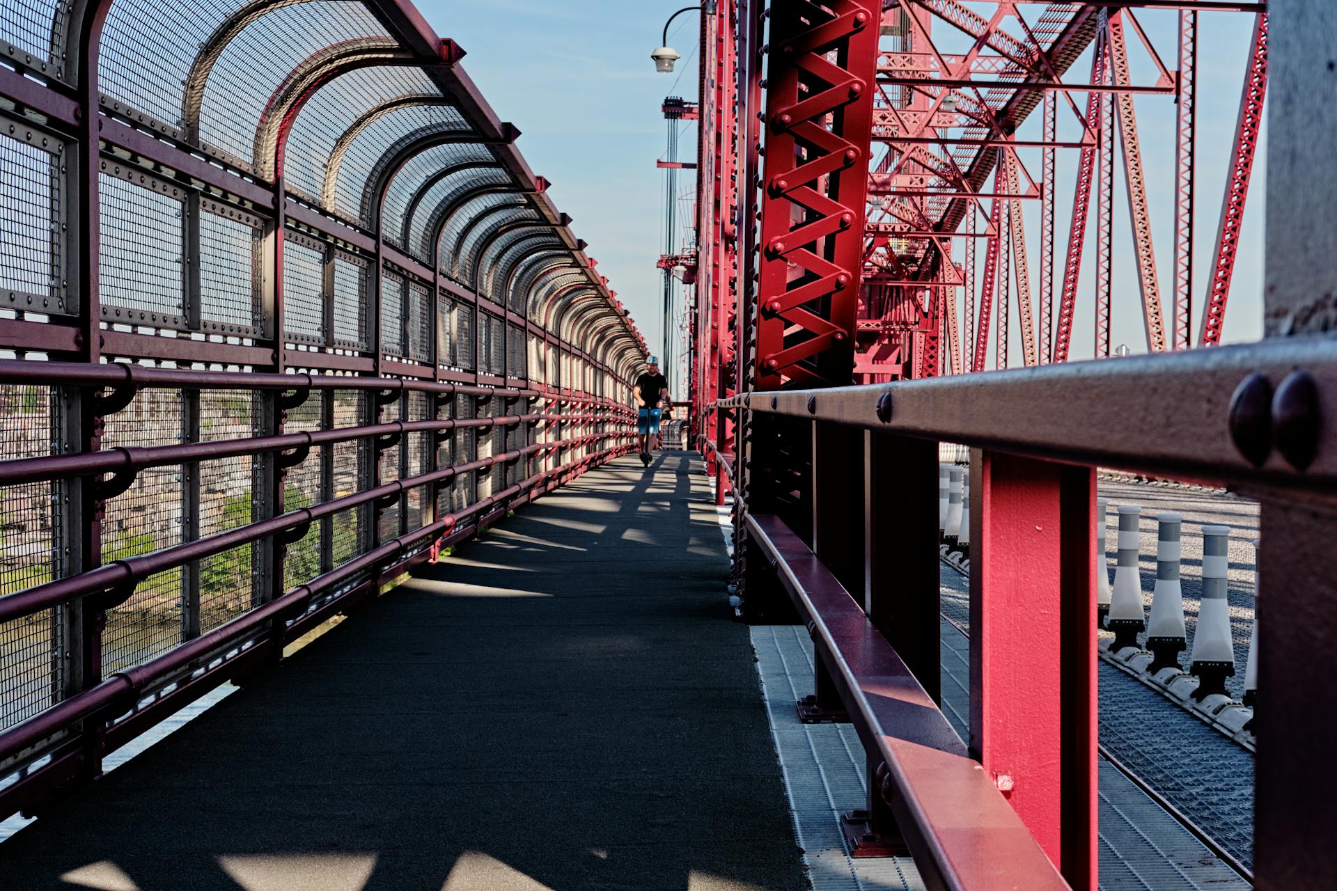 Steel truss pedestrian path on Williamsburg Bridge in New York City, vibrant metal architecture.