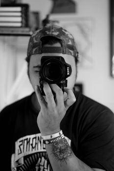 Black and white of anonymous young tattooed guy in trendy outfit and cap taking photo on digital camera - Fotografer Sidoarjo