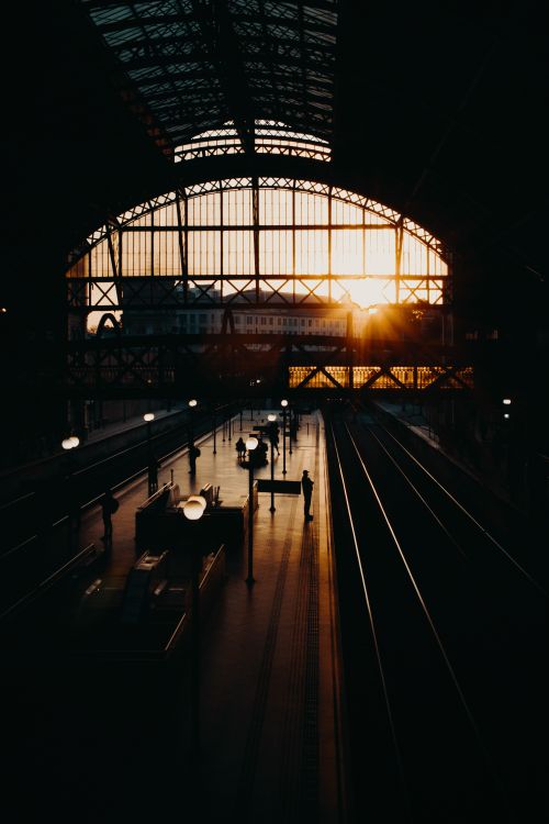 Free From above of distant unrecognizable people standing in dark railroad station with glass walls at sundown Stock Photo