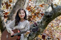 Woman in White Floral Dress Playing Brown Acoustic Guitar