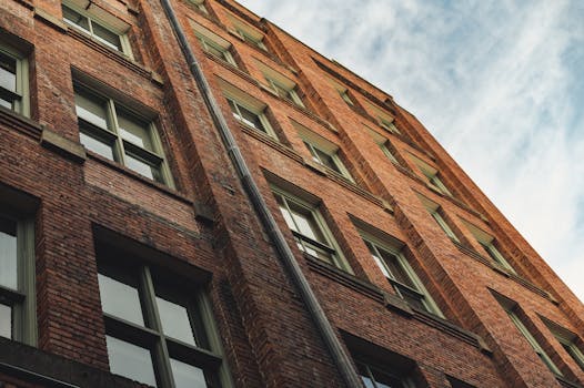 Low angle view of a modern brick residential building against a cloudy blue sky.