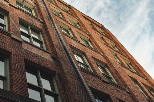 Free From below of modern building facade with brick walls and windows against cloudy blue sky Stock Photo