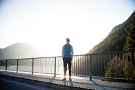 日落时分，一名男子站在德国伦格里斯的一座桥上，四周群山环绕