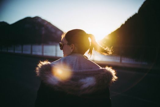 在德国伦格里斯，一位穿着毛皮领外套的女子正欣赏日落景色和山脉的轮廓