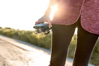 一个女人在阳光明媚的道路上拿着无人机，展现了现代科技与冒险精神