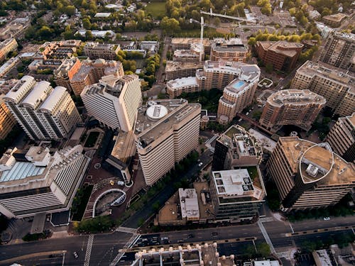 Drone view of creative geometric buildings and green areas in residential district of modern city