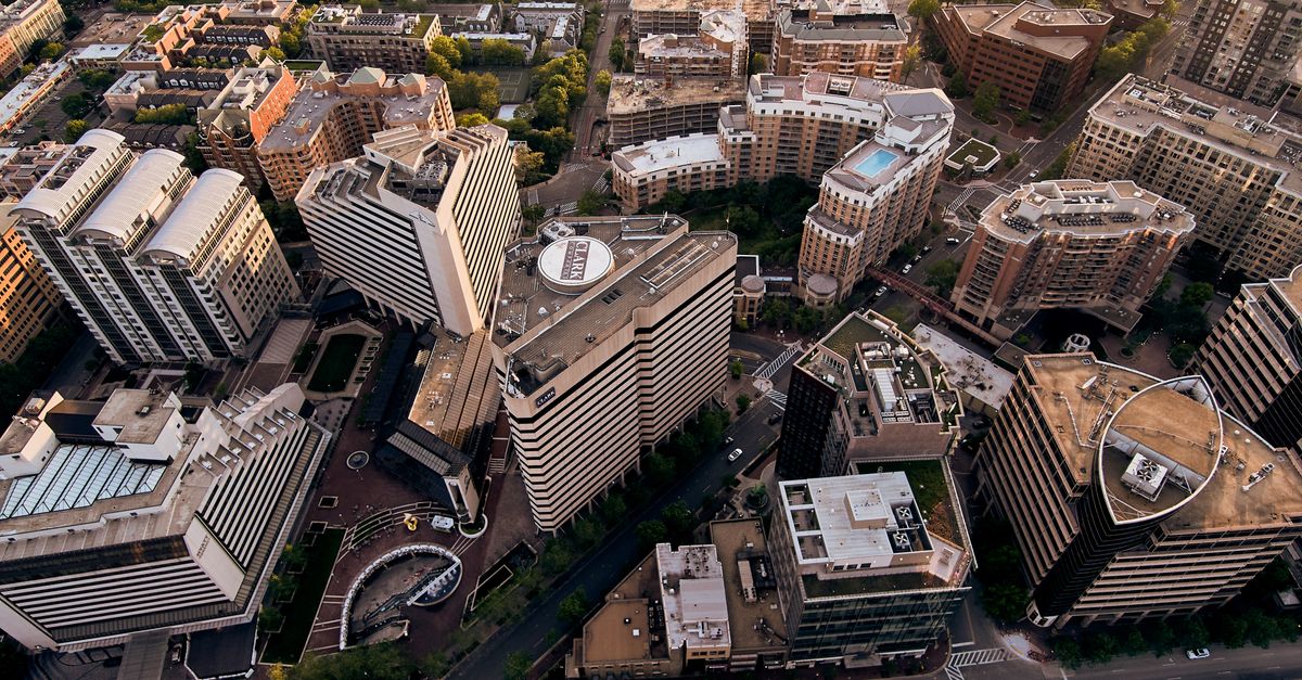 Drone view of creative geometric buildings and green areas in residential district of modern city
