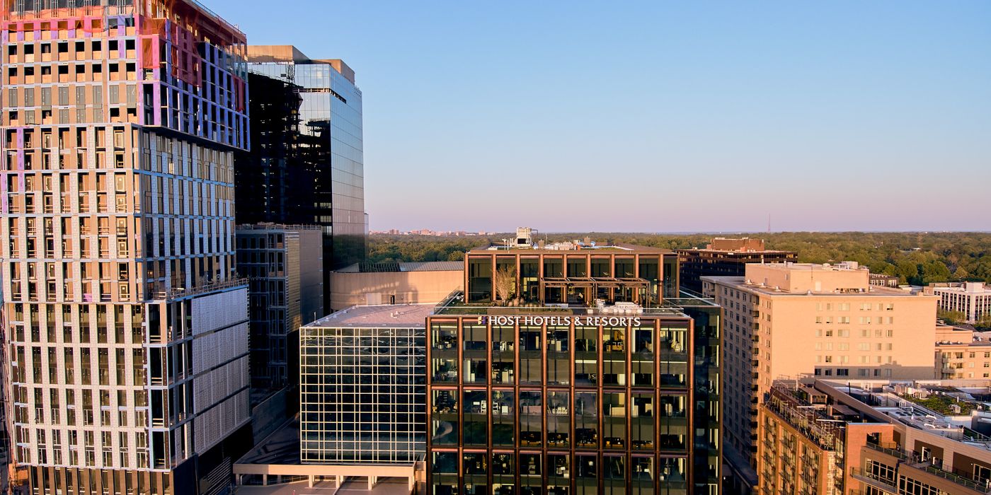 Modern hotel tower rising above a city skyline at dusk