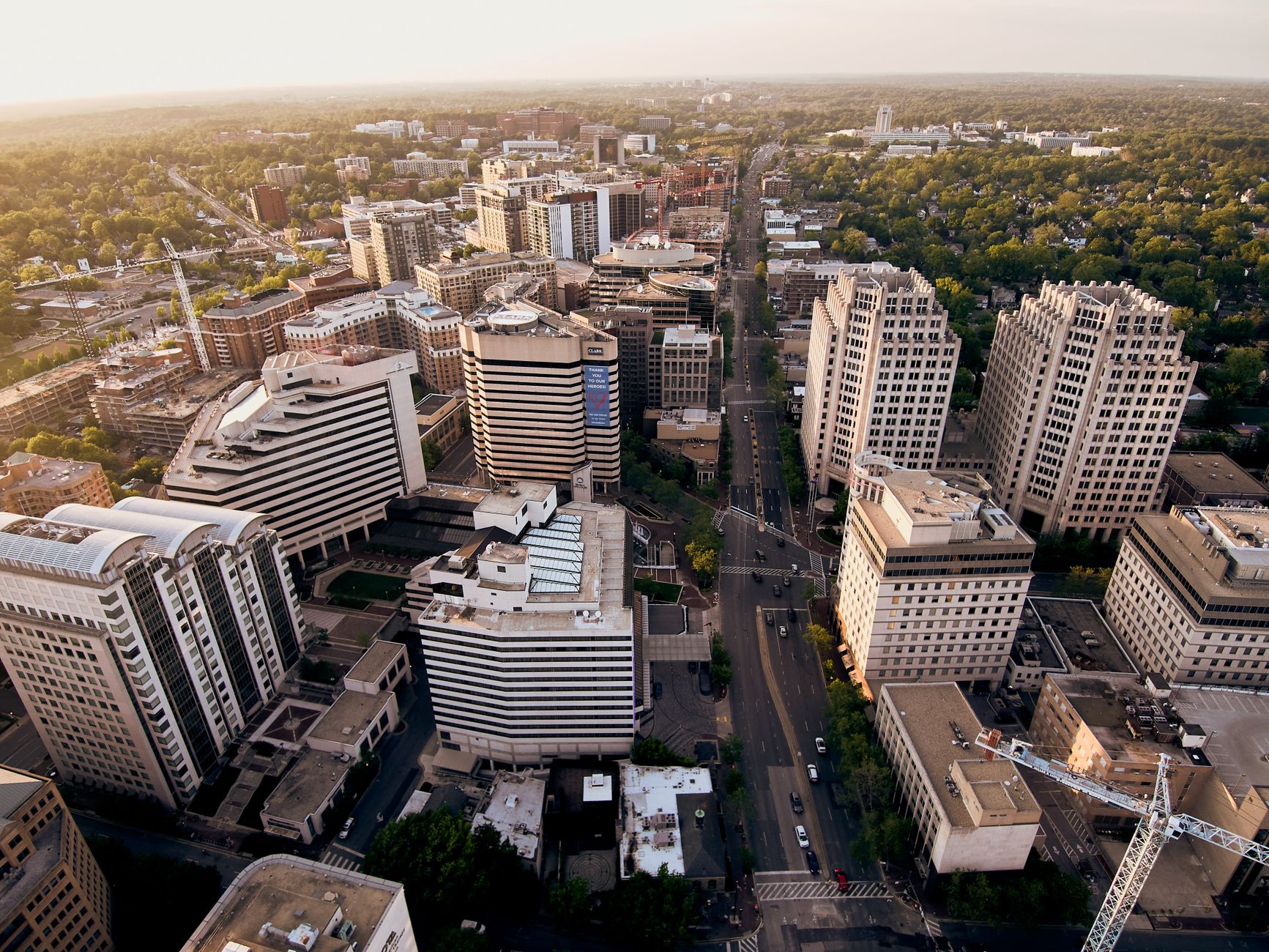 Drone view modern white residential buildings located in green city district near vast park in daylight