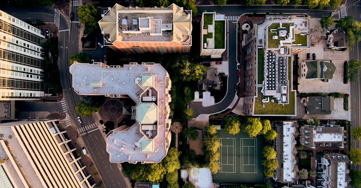 Drone top view of contemporary metropolis city complex with decent dwelling and public spaces amidst green trees