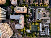 Drone top view of contemporary metropolis city complex with decent dwelling and public spaces amidst green trees