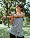 Serious Asian sportswoman stretching muscles before workout in nature