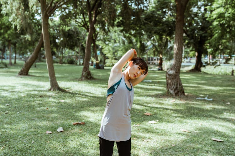 Concentrated Ethnic Sportswoman Stretching Muscles Of Arm And Back In Park