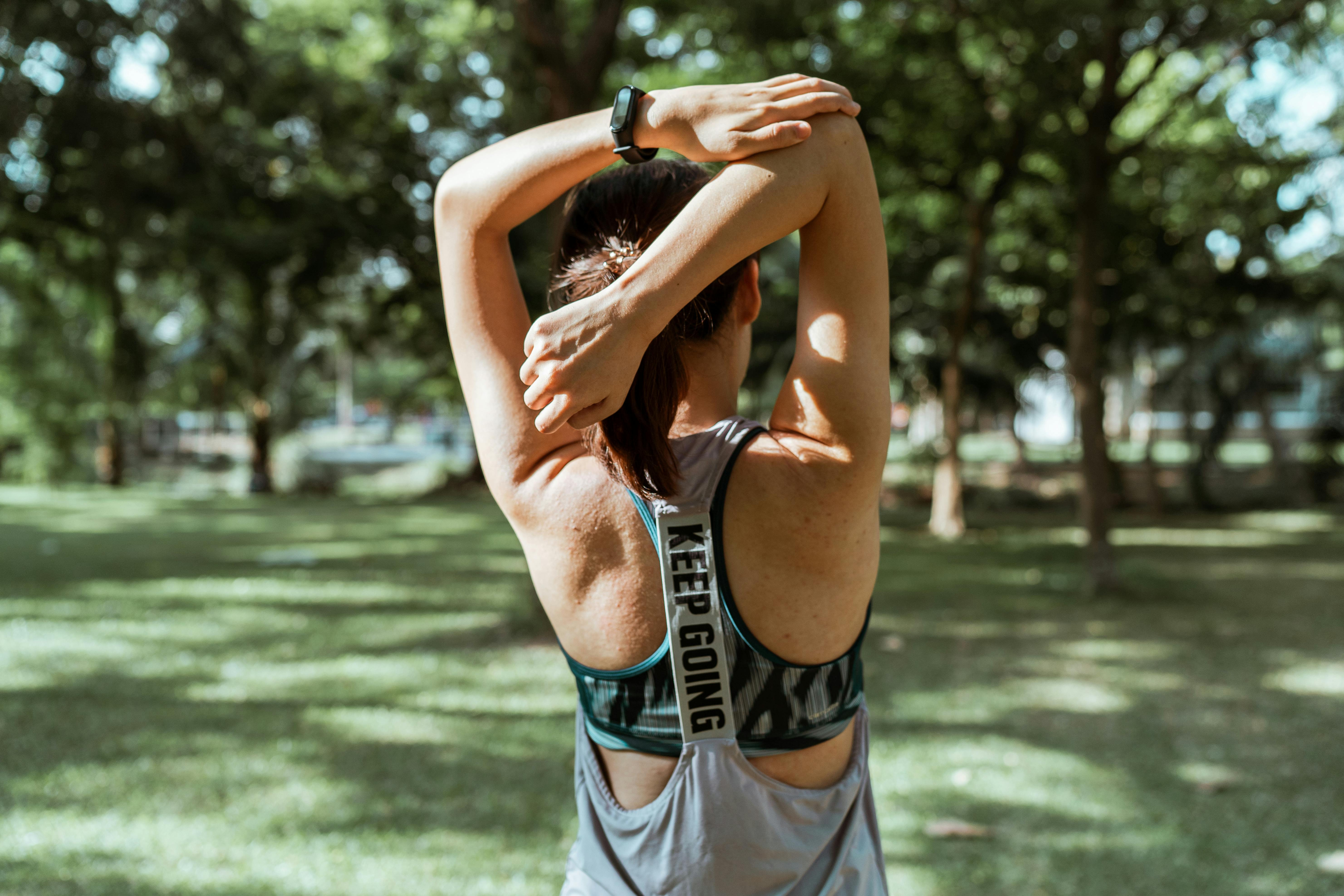 unrecognizable female athlete stretching muscles of arms and back