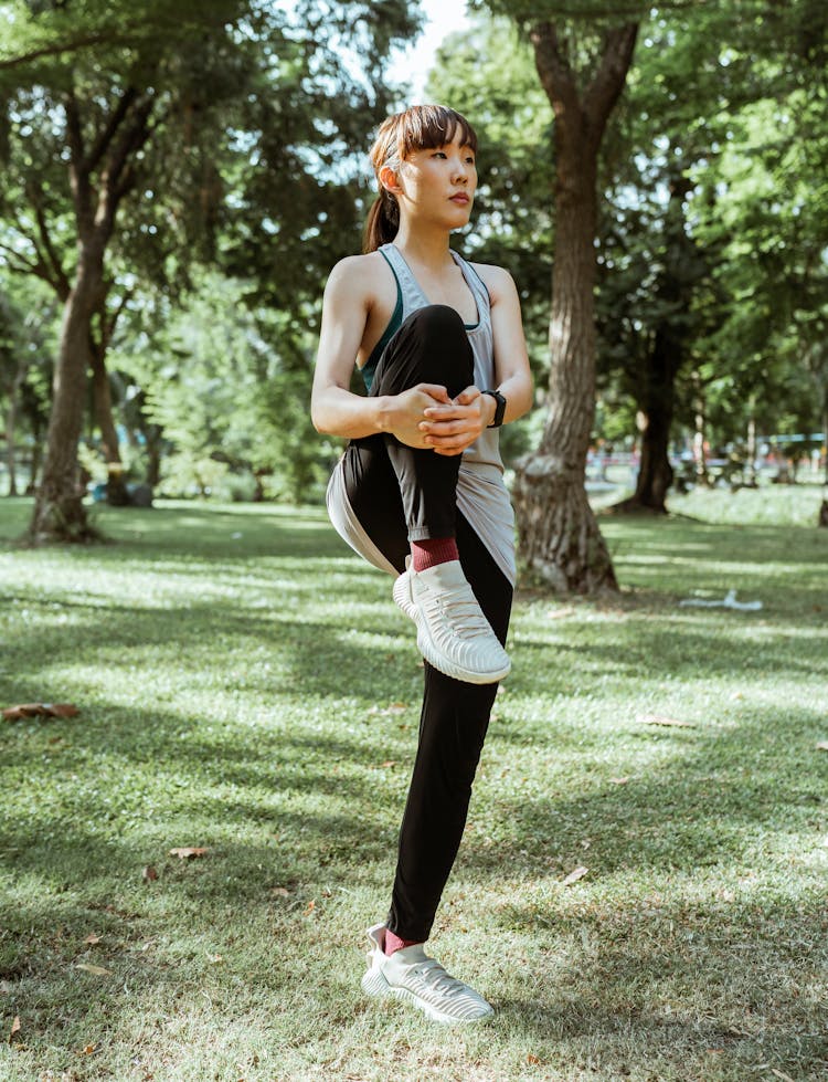 Sporty Asian Woman Stretching Muscles In Park