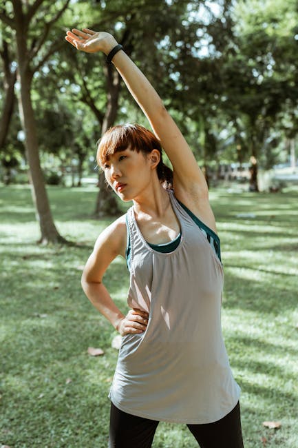 Serious Asian sportswoman stretching muscles in park · Free Stock Photo