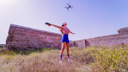 Fit woman standing with arms outstretched under flying drone