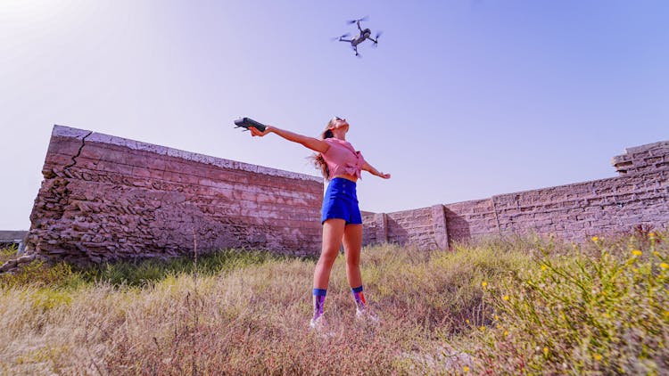 Fit Woman Standing With Arms Outstretched Under Flying Drone