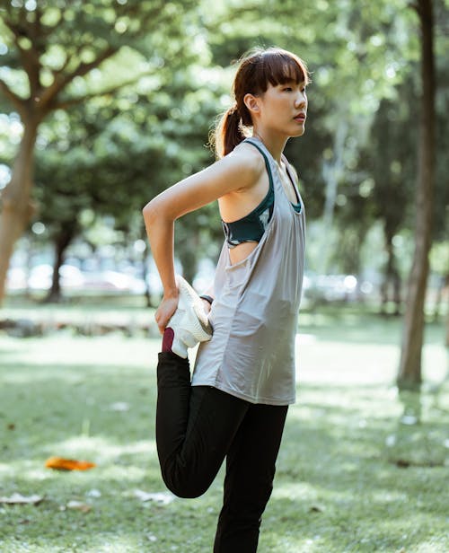 Free Concentrated sportswoman doing quad stretch in park Stock Photo