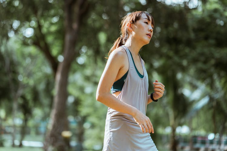 Fit Tired Sportswoman Jogging In Sunny Park