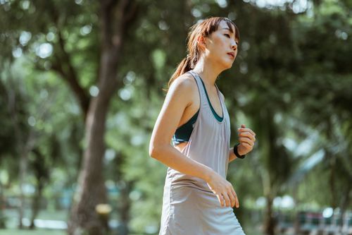 Free Side view of determined tired Asian female jogger in sportswear running in green park during sunny summer day Stock Photo