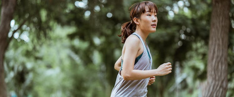 Positive Asian Sportswoman Jogging In Countryside