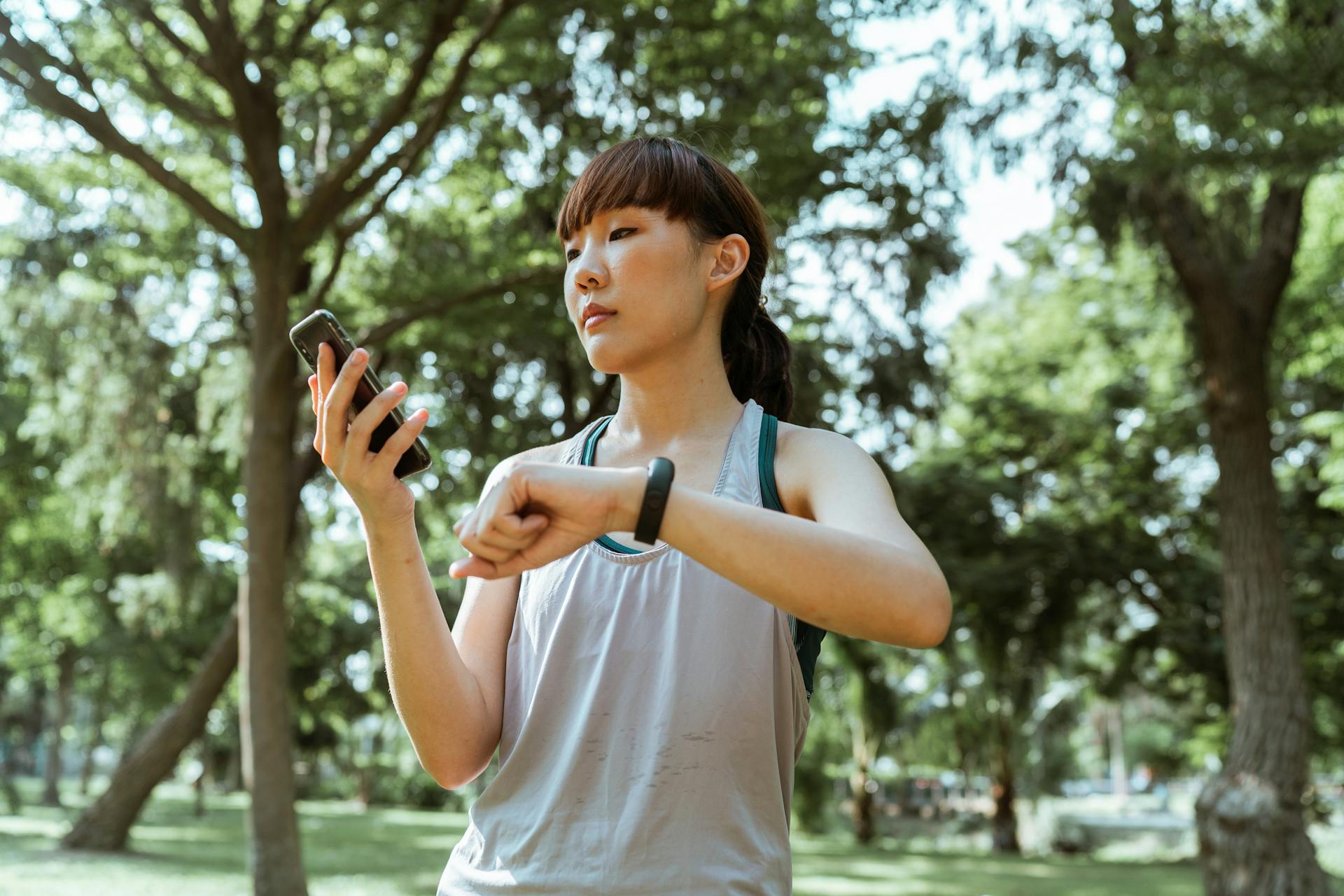 Content sportswoman using smartphone and fitness tracker