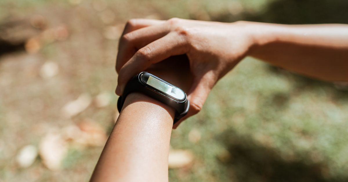 A woman outdoors checking the fitness band on her wrist
