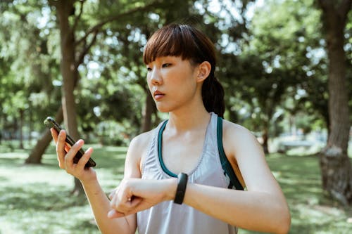 Free Concentrated young Asian woman using smartphone in park Stock Photo