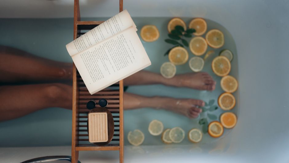 Enjoy a soothing bath with citrus slices, natural soap, and a good book for ultimate relaxation.