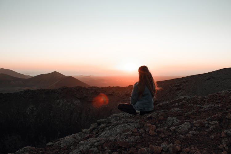 Woman Sitting On Mountain Top