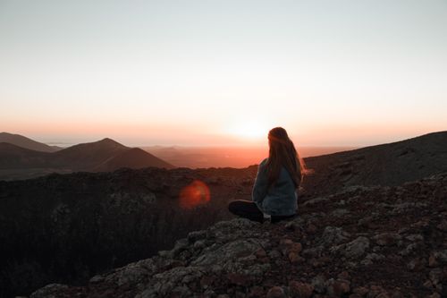 Free A woman meditates at sunrise in a serene mountain landscape, capturing tranquility. Stock Photo