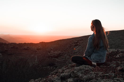 A woman watches the sunset over the rocky landscape, embracing the serene atmosphere.