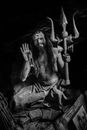 Calm voodoo priest with trident sitting on ground