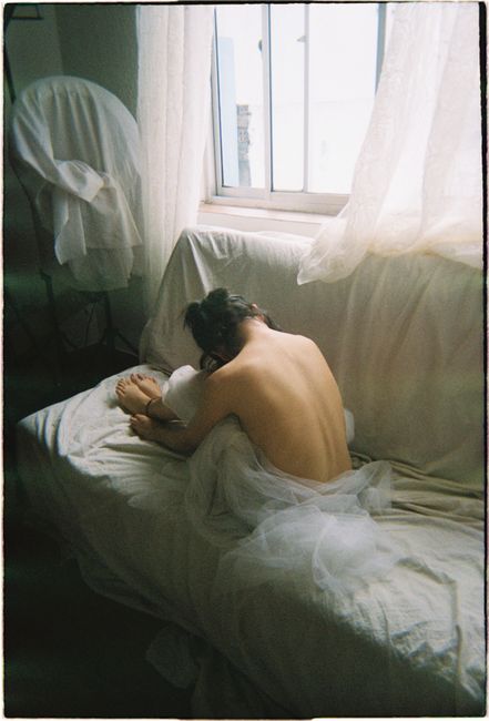 Serene portrait of a woman resting on a sofa, bathed in soft morning light from a window.