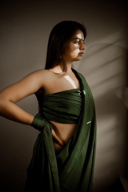 Free Elegant portrait of an Indian woman in a green saree posing with a thoughtful expression indoors. Stock Photo
