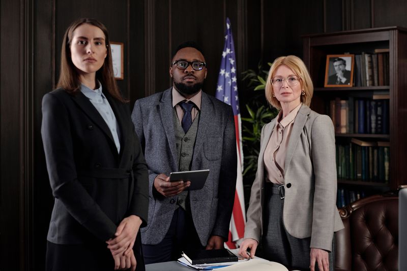 Three attorneys standing in a wood-paneled law office with an American flag